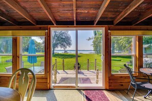 Een houten chalet met een schuifdeur naar een terras. Binnen is een tafel en een stoel.