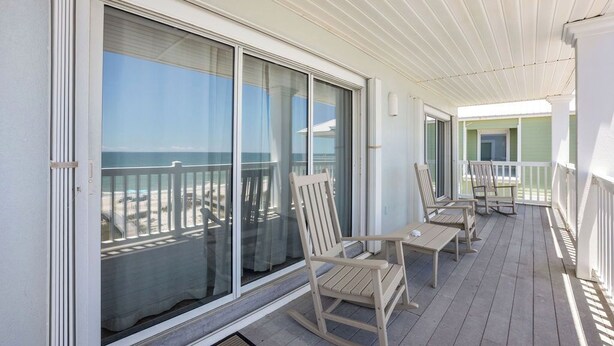 Een balkon met uitzicht op de oceaan, een schommelstoel en een tafel.