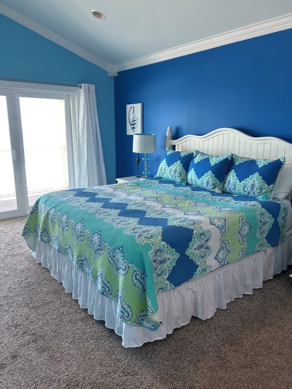 A bedroom with a blue wall, white bed frame, and a patterned bedspread. - Gorgeous Gulf Front Home, 8 bed/7 bath, Pool, Elevator, and all the amenities! (Saint George Island)