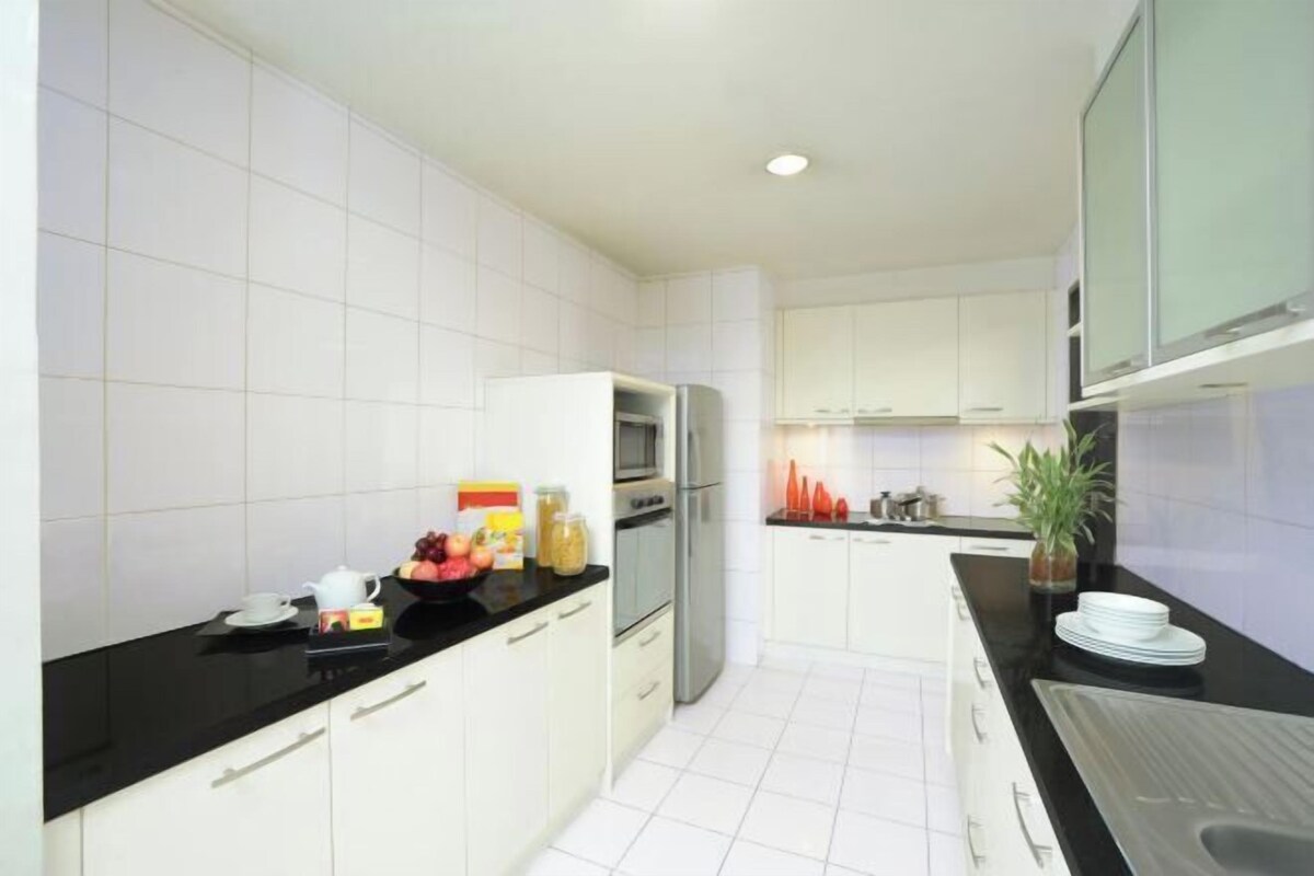 A modern kitchen with white cabinets, a black countertop, and stainless steel appliances.