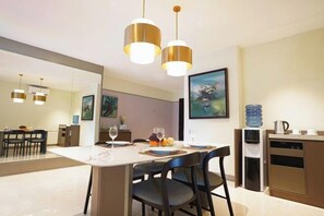 A modern dining area with a marble table, black chairs, and pendant lighting. - Somerset Berlian Jakarta (South Jakarta)