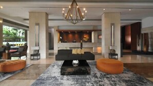 A modern lobby with a central seating area, a chandelier, and a reception desk.