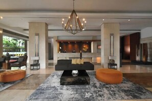 Een moderne lobby met een centrale zithoek, een kroonluchter en een receptiebalie.