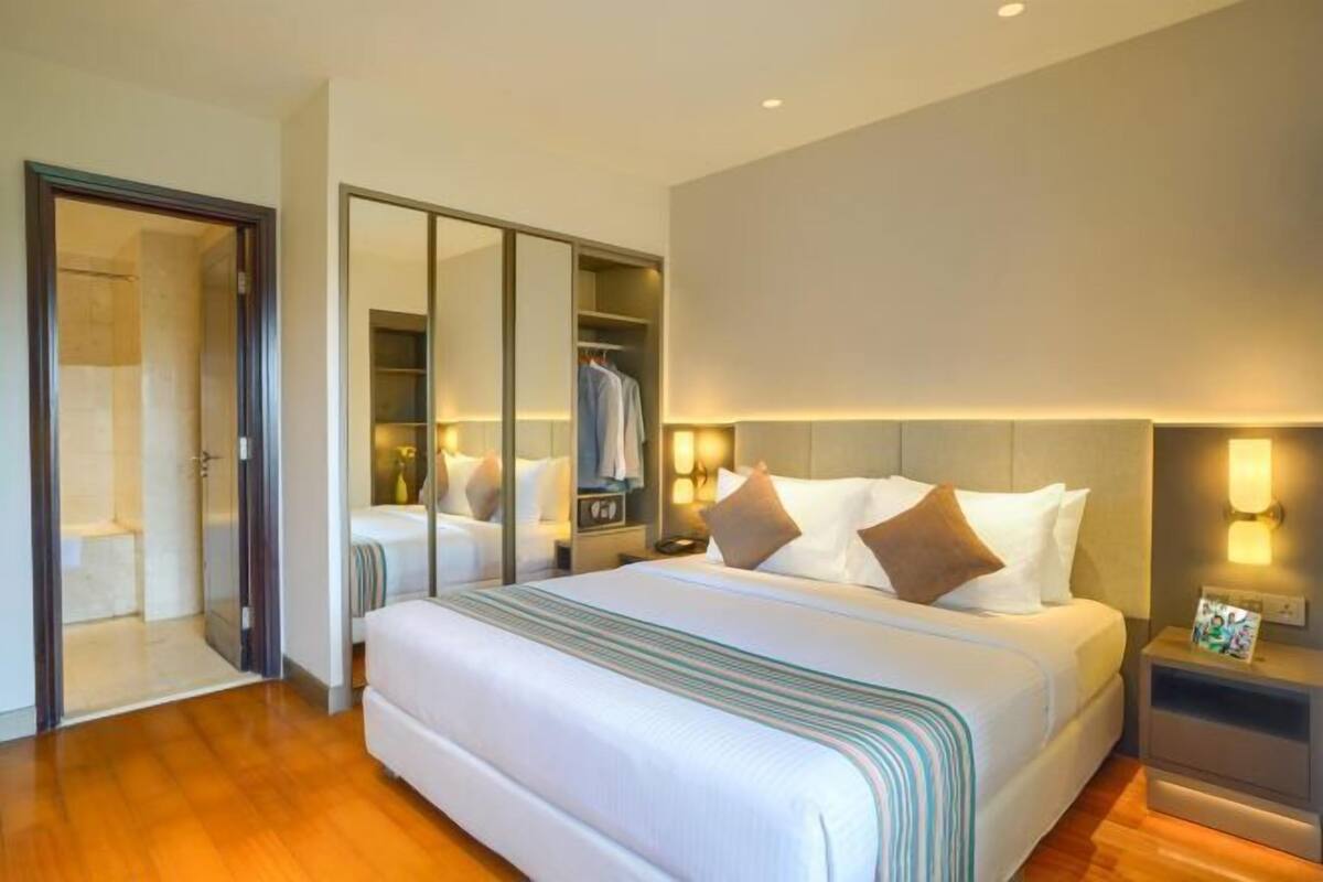 Une chambre d’hôtel avec un grand lit, un dressing et une salle de bain avec douche.