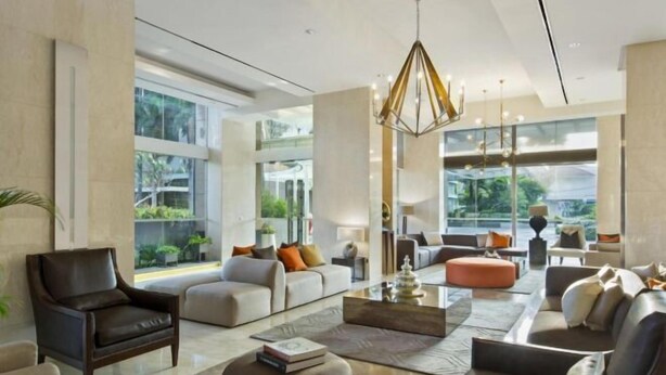 A spacious living area with modern furniture, large windows, and a view of greenery outside.