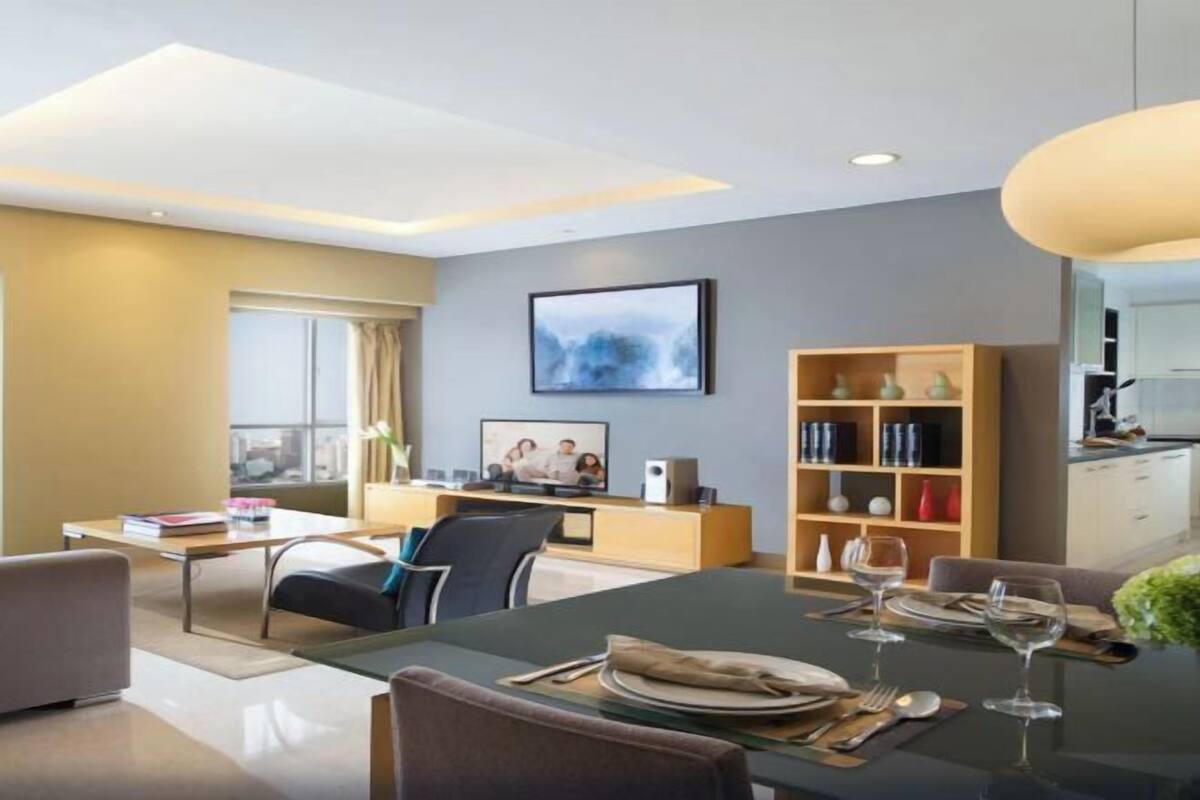 Une chambre d’hôtel moderne dotée d’un coin repas, d’une bibliothèque et d’un téléviseur.
