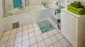 Ein Badezimmer mit einer gläsernen Duschkabine, einer weißen Badewanne, einem Waschbecken und einem Heizkörper.