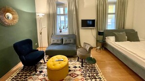 Ein modernes Schlafzimmer mit Sofa, Hocker, Sessel und Bett.