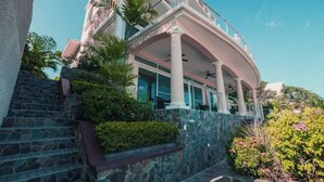 A multi-story building with a curved roof, stone steps, and a balcony with outdoor seating. - Conch – Oceanfront Ground-Floor Studios – Panama (San Carlos)
