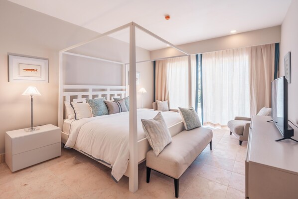 A modern bedroom with a canopy bed, a bedside table, a bench, and a TV.