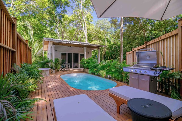 A backyard with a swimming pool, a barbecue grill, and a small building.