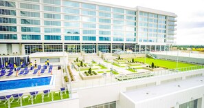 Ein modernes Hotel mit Poolbereich auf dem Dach, Sitzgelegenheiten im Freien und einer großzügigen Fassade.