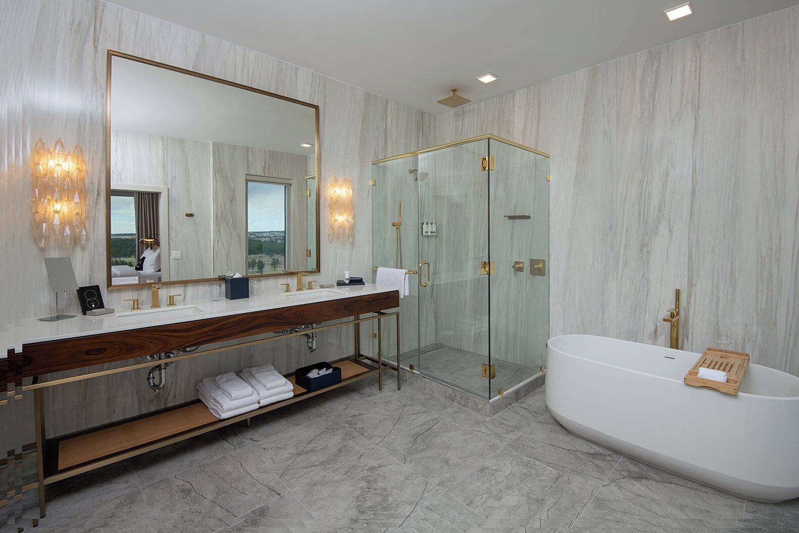 Un baño moderno con un espejo grande, lavamanos dobles, ducha con cerramiento de vidrio y una bañera independiente.