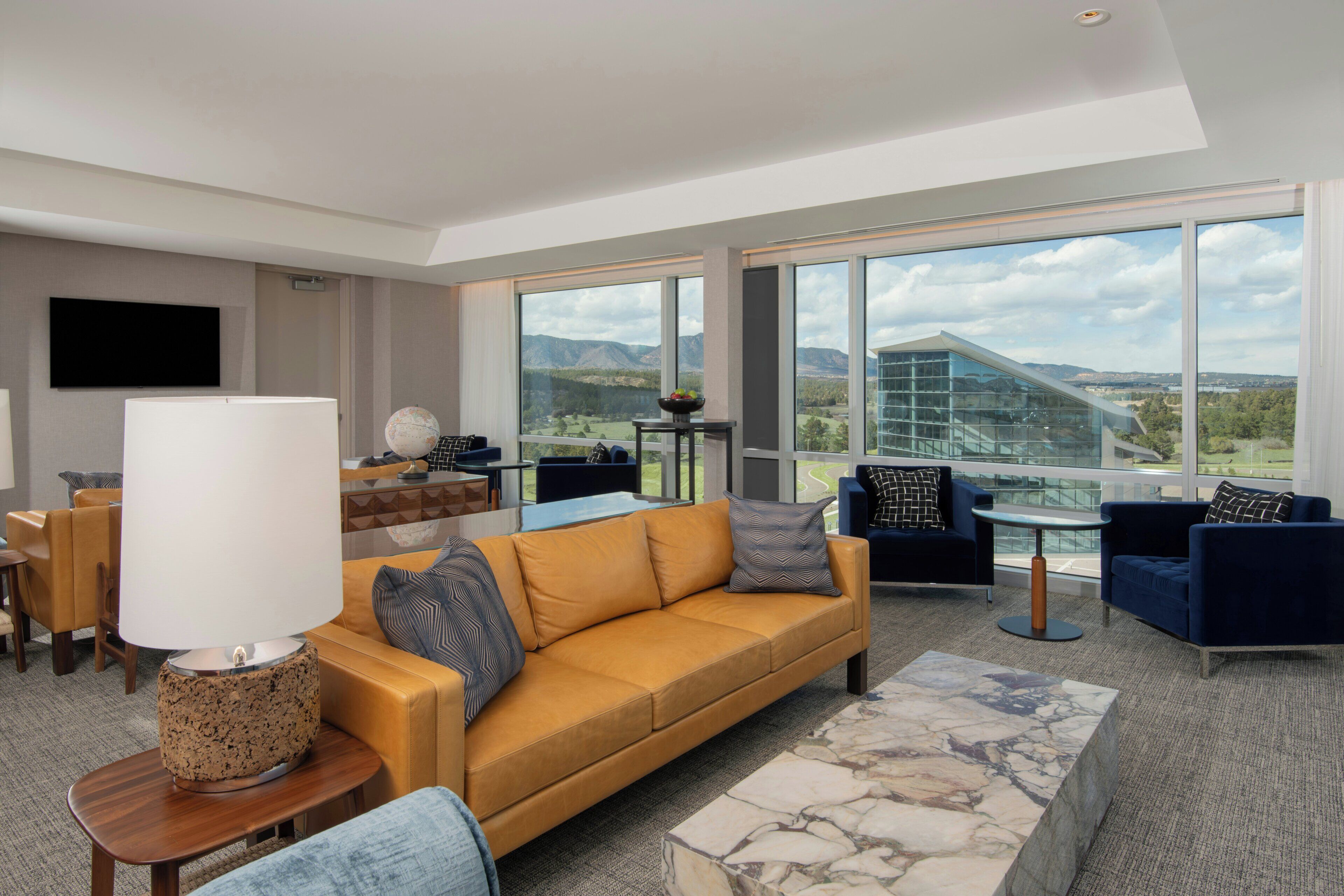 A modern living room with a sofa, armchairs, a coffee table, and a TV.