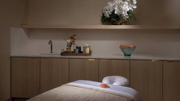 Un dormitorio moderno con una cama, una mesita de noche, un tocador con espejo y una estantería con objetos decorativos.