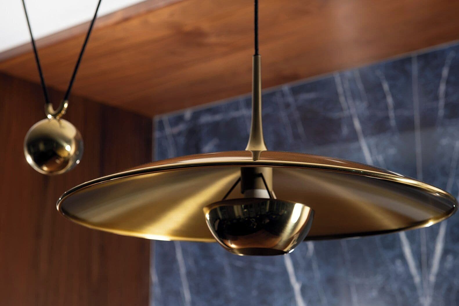 A pendant light fixture with a metallic finish and a spherical element hanging from the ceiling.