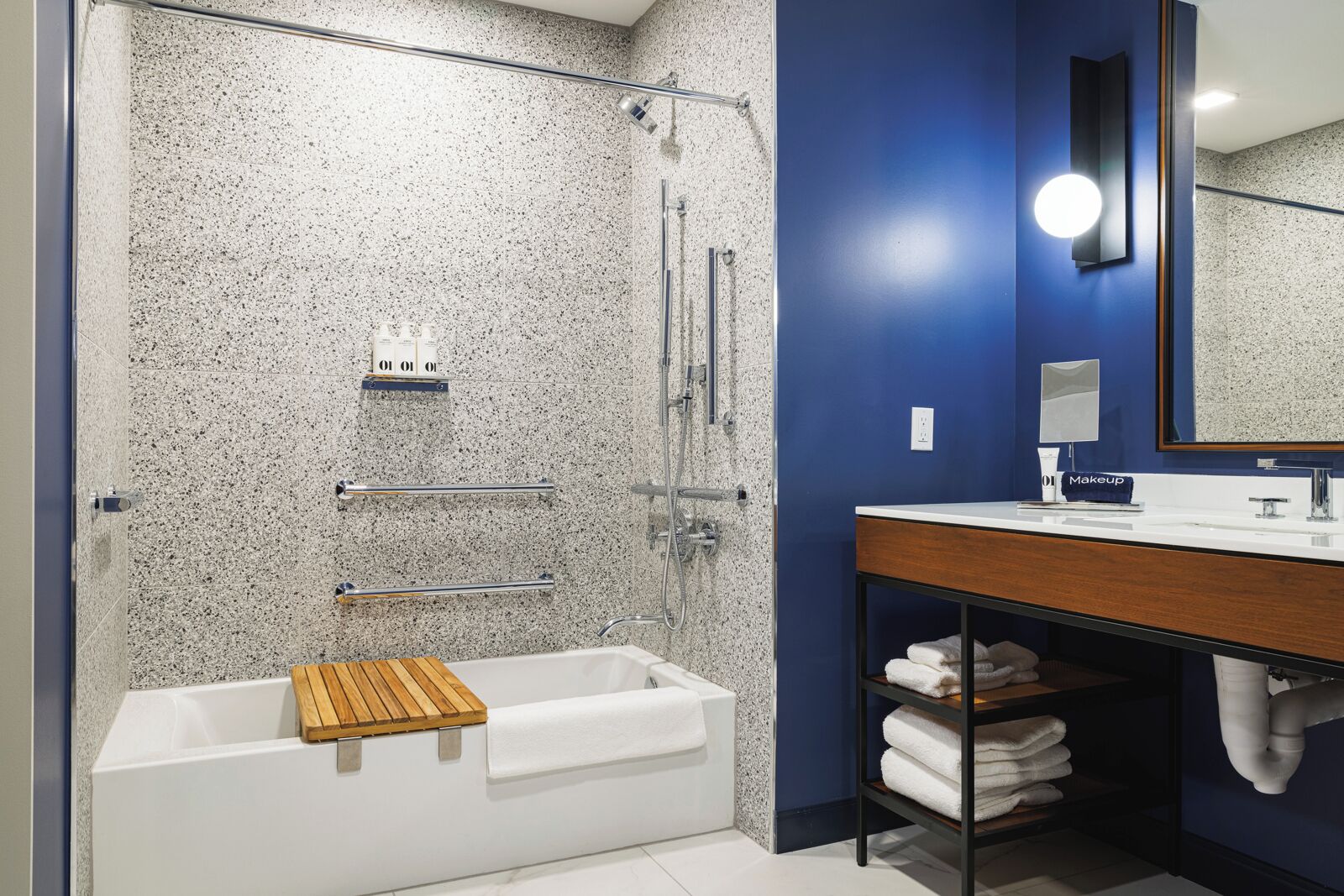 A modern bathroom with a freestanding bathtub, a shower enclosure, and a vanity with a mirror and towel rack.