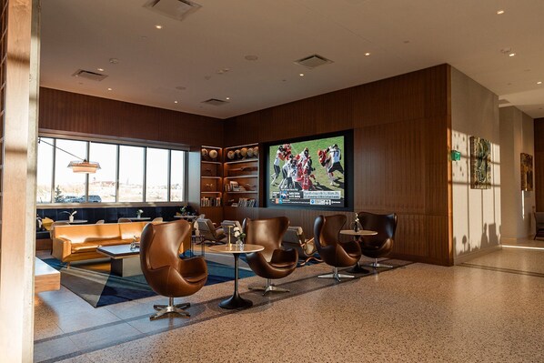 Un área de estar moderna con sofás de cuero, un televisor de pantalla plana grande y una estantería con objetos decorativos.
