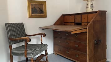 Et værelse med et træskrivebord, en stol, en lampe og et billede i ramme på væggen.