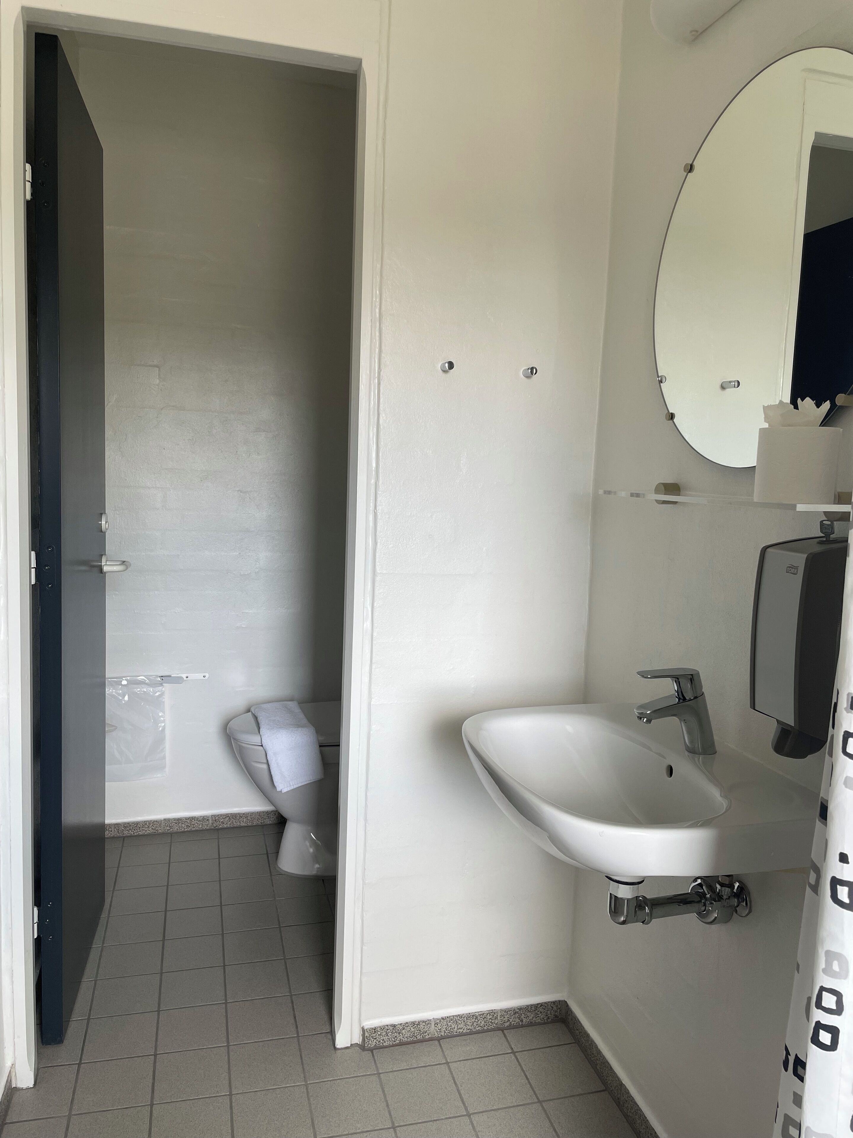 Een badkamer met toilet, wastafel en spiegel.