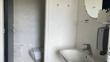 Een badkamer met toilet, wastafel en spiegel.