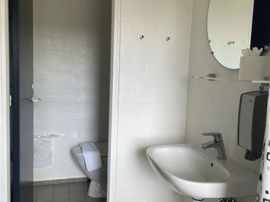 Een badkamer met toilet, wastafel en spiegel.