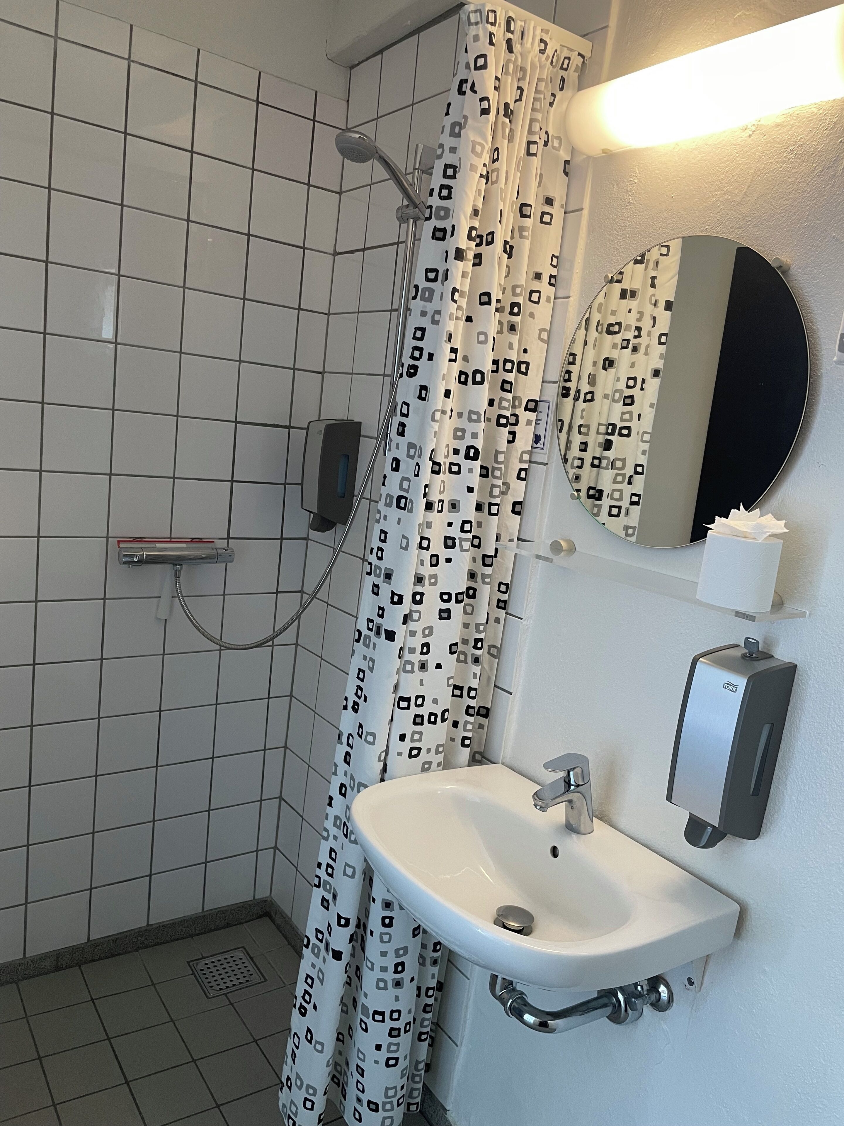 Un baño con ducha, inodoro, lavamanos y un secador de manos.