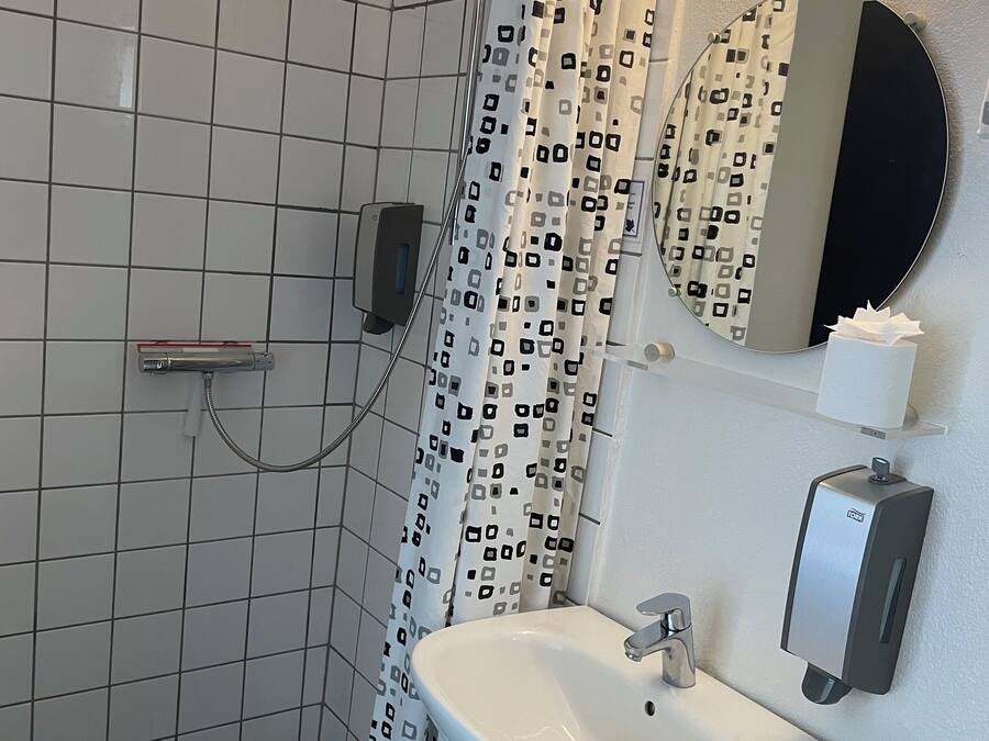 Un baño con ducha, inodoro, lavamanos y un secador de manos.