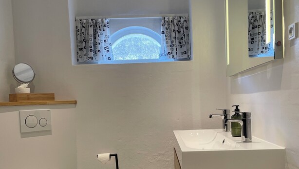Une salle de bain moderne équipée de toilettes, d’un lavabo et d’un miroir.