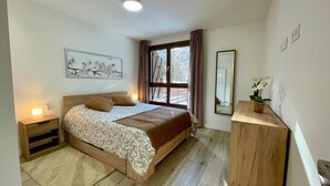 Une chambre à coucher comprenant un lit, une table de chevet, une commode, une fenêtre avec des rideaux et un miroir fixé au mur.