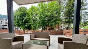 Un espace extérieur aménagé en terrasse, avec des meubles en osier, notamment des canapés et une table basse, le tout abrité par un toit.