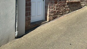 A building with a white door, a small window, and a stone wall.