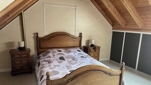 A bedroom with a wooden bed, two nightstands, a lamp, and a wardrobe.