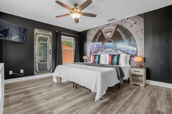 Cozy retreat with a large bed, ceiling fan, and window with curtains.