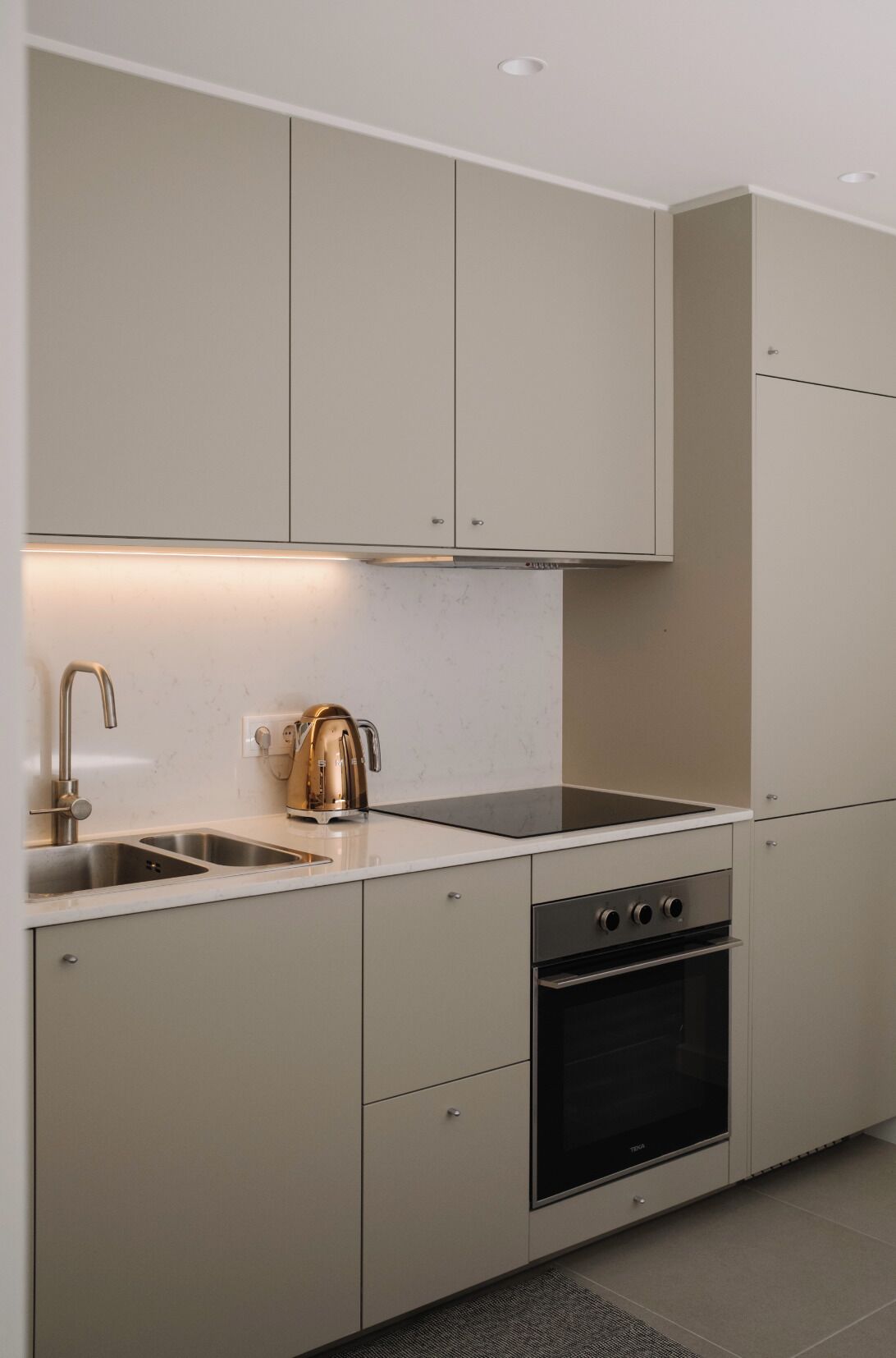 Une cuisine moderne équipée d’un four encastré, d’une plaque de cuisson et d’un évier.
