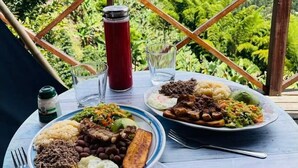 Una mesa con comida y un termo en un balcón con vistas a la montaña.