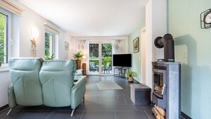 Una sala de estar moderna con un sofá, una chimenea, un televisor y vistas al exterior.