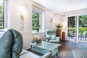 Un salon moderne avec une table basse en verre, un fauteuil vert clair et un canapé.