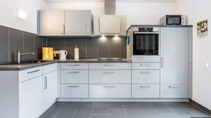Una cocina moderna con armarios grises, horno empotrado y microondas encima.
