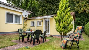 A patio with a table and chairs, a small tree, and a house with a satellite dish. - Apartment 'Prerow Am Deich - 4' with Private Terrace, Private Garden and Wi-Fi (Ostseebad Prerow)