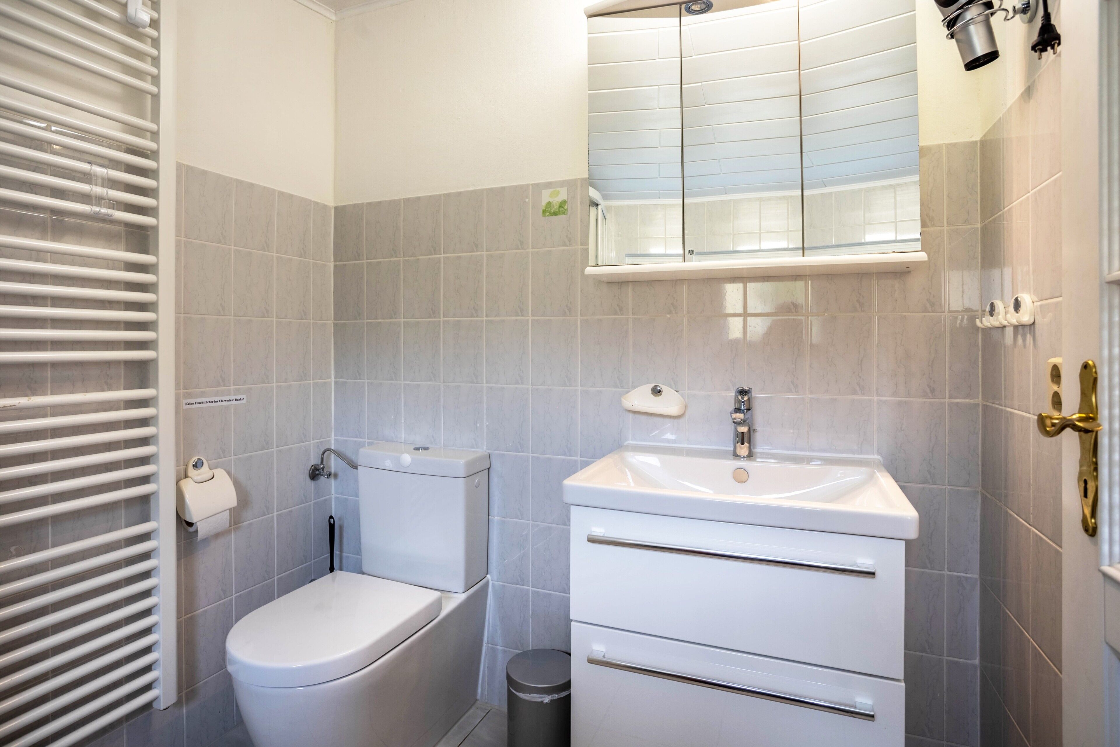 Et badeværelse med toilet, håndvask og spejl.