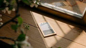 Un libro rilegato intitolato 'Salon' su un tavolo di legno, con una finestra sullo sfondo.