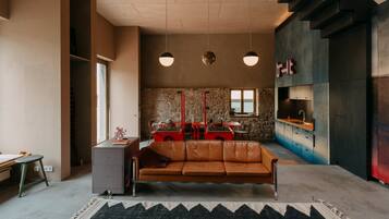 Ein modernes Wohnzimmer mit Ledersofa, Essbereich und einer Küche mit Steinwand.