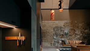 A modern interior with a stone wall, a wooden bench, a sofa, and hanging pendant lights. - Holiday Home Feuer & Flamme – Your Retreat in Jena-Kunitz by the Saale (Jena)