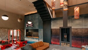 A modern living room with a sofa, a fireplace, a kitchen area, and a staircase. - Holiday Home Feuer & Flamme – Your Retreat in Jena-Kunitz by the Saale (Jena)