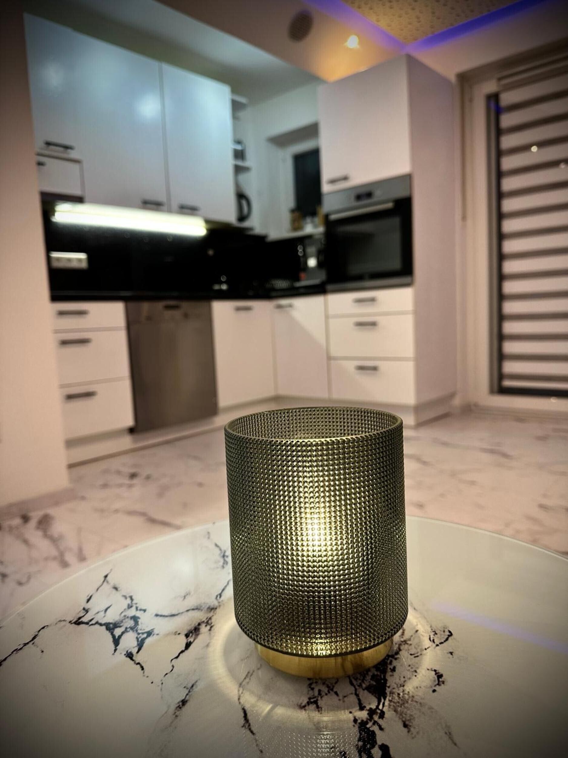 A modern kitchen with white cabinets, a black countertop, and a decorative metal vase on a marble table.
