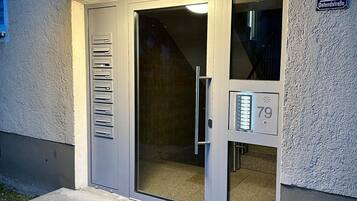 A building entrance with a glass door, a metal mail slot, and a sign indicating the address '79 Ostendstrasse.'