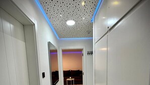 A hallway with white walls, a marble floor, and a ceiling with perforated panels.