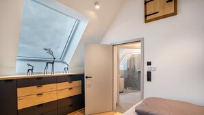 Une chambre dotée d’une lucarne, d’une armoire, d’un lit et d’une porte donnant sur une salle de bain.