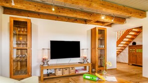 A living room with a TV, wooden cabinets, a staircase, and a wooden ceiling. - Apartment 'Gästehaus Wüpping 3' with Mountain View, Private Terrace and Wi-Fi (Salem)